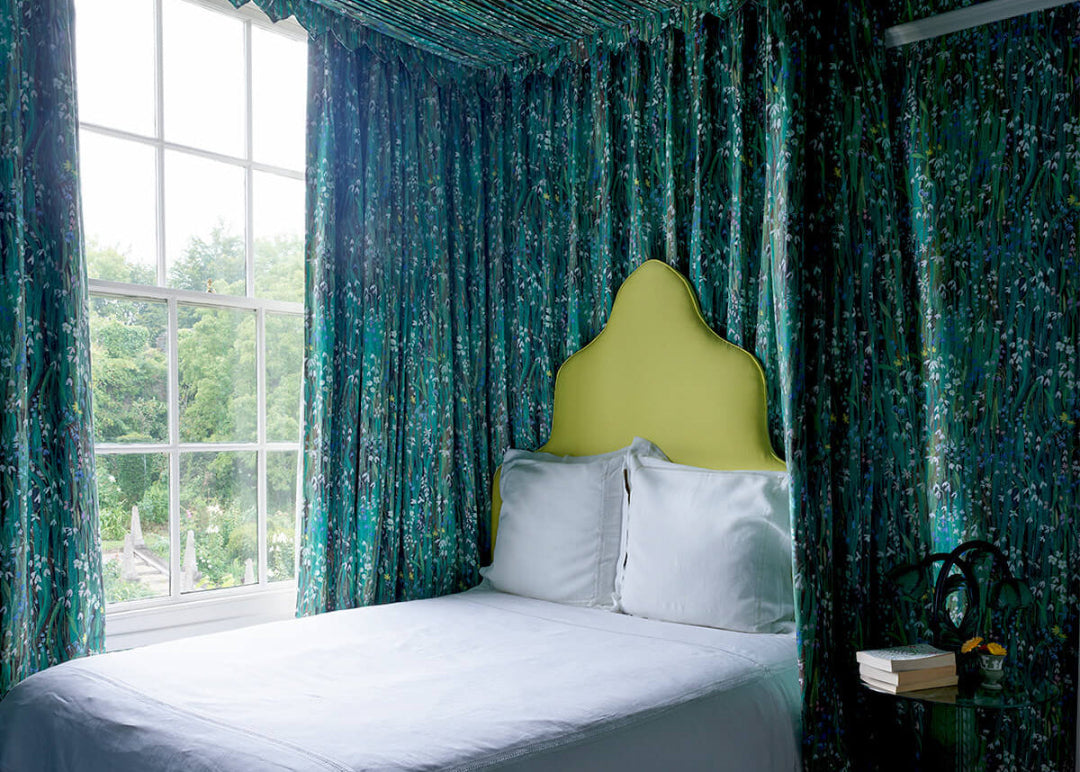 a bed with a green headboard and blue curtains